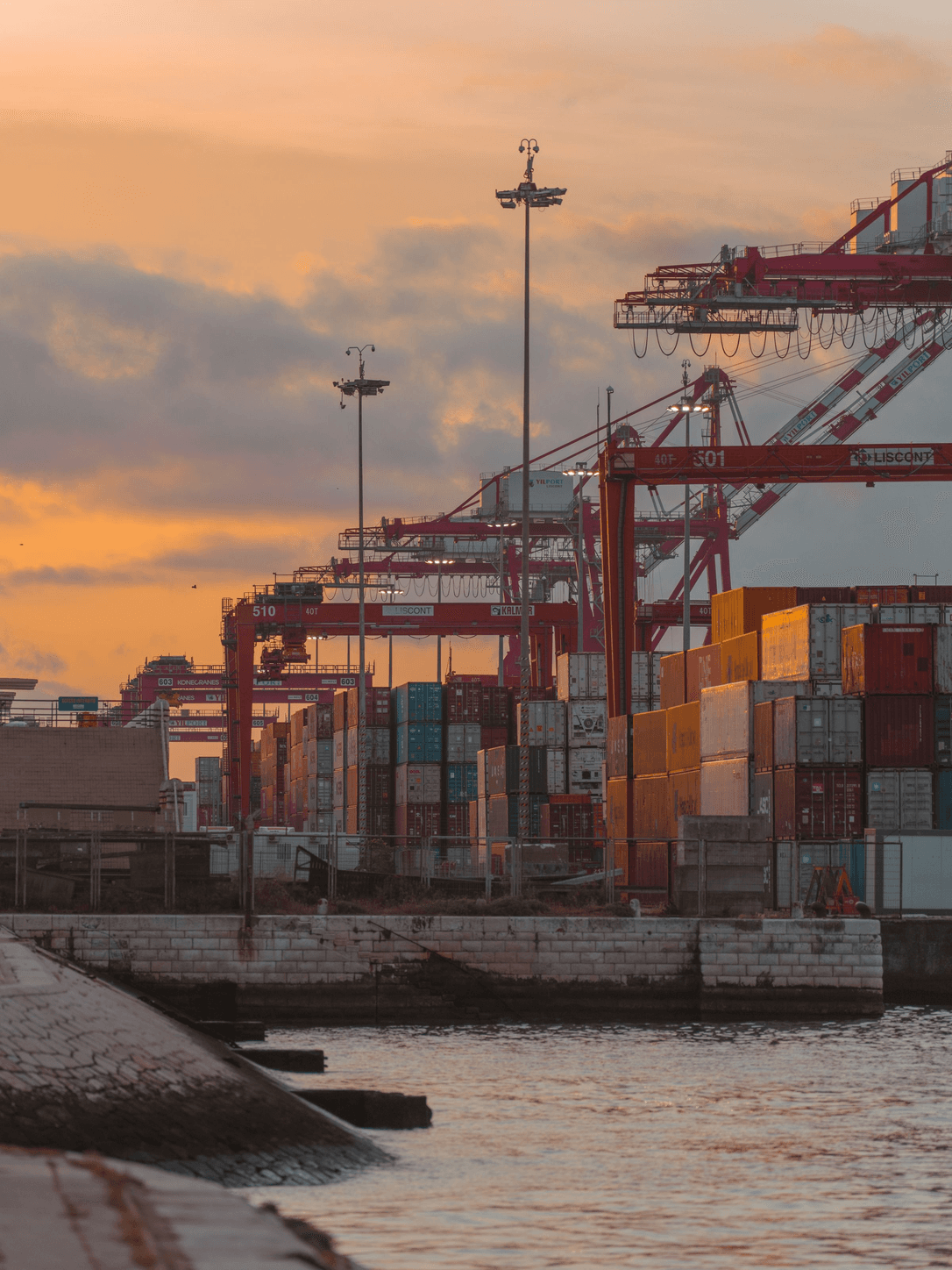 Container port with cranes at sunset